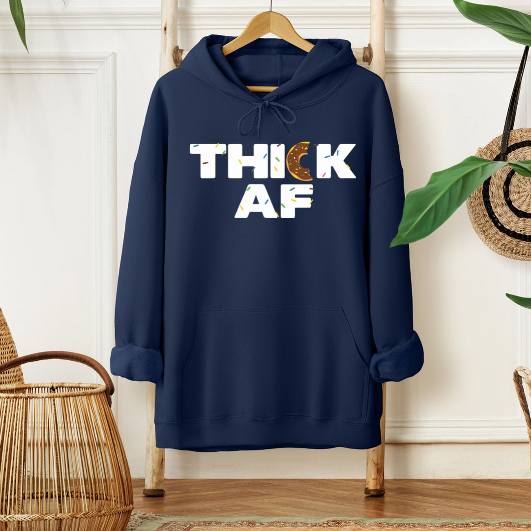 Navy blue hoodie with the text 'THICK AF' printed on the front, displayed on a wooden hanger with a wicker basket in the background.