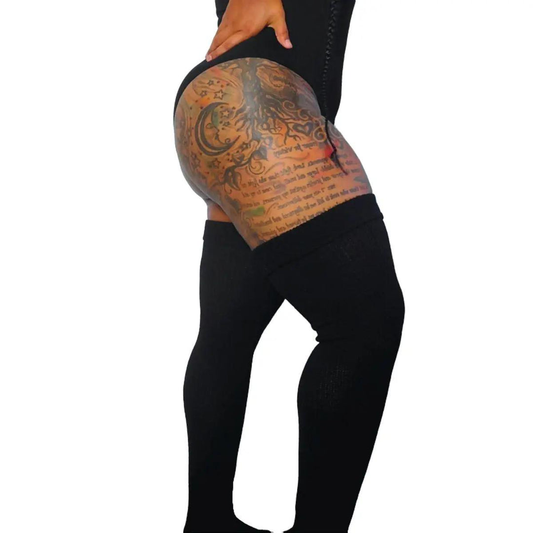 A person wearing black thigh-high socks, showcasing the sock's stretch and fit on a leg with a tattoo.
